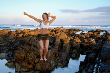 Flexible yoga instructor stretching on the beach