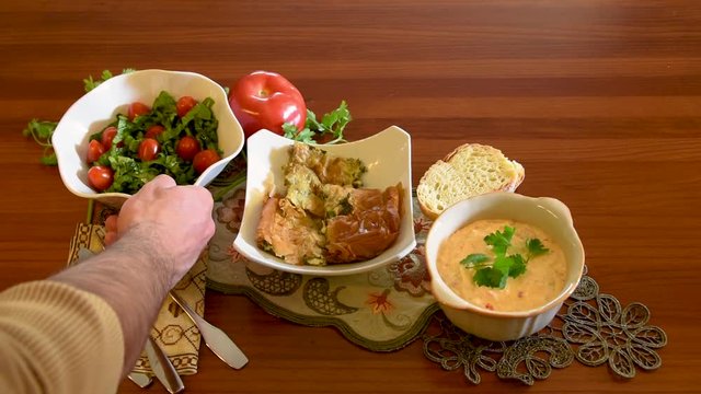 Healthy mediterranean cuisine, three dishes concept for lunch or dinner. Side view closeup of getting the letuce salad from the table in slow motion