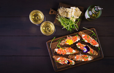 Salmon sandwiches with cream cheese and microgreen on wooden table. Canape with salmon. Top view