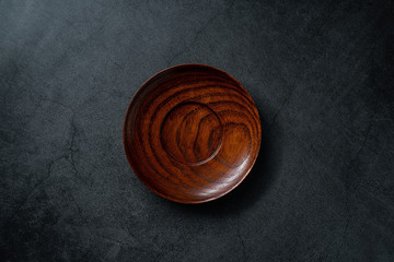 An empty wooden dish on a black background