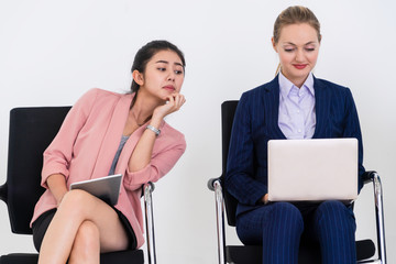 Curious businesswoman looking at the screen of laptop computer of another businesswoman spying...