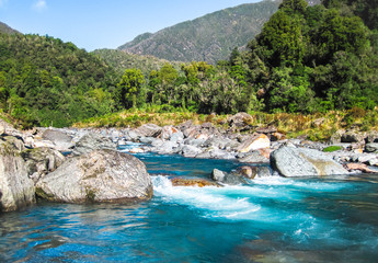 The Toaroha River radiating a deep blue/aqua color on a sunny day on the south island of New Zealand.