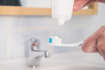 Fototapeta na wymiar Person putting toothpaste on toothbrush