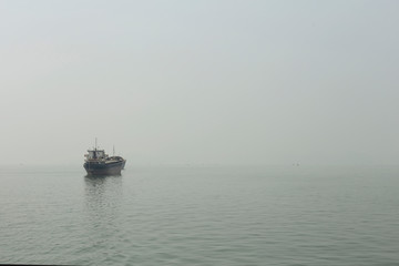 Fototapeta na wymiar Merchant ship in the haze of Halong Bay