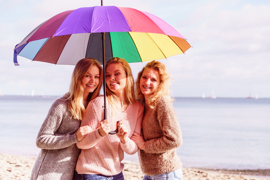 Three women under colorful umbrella