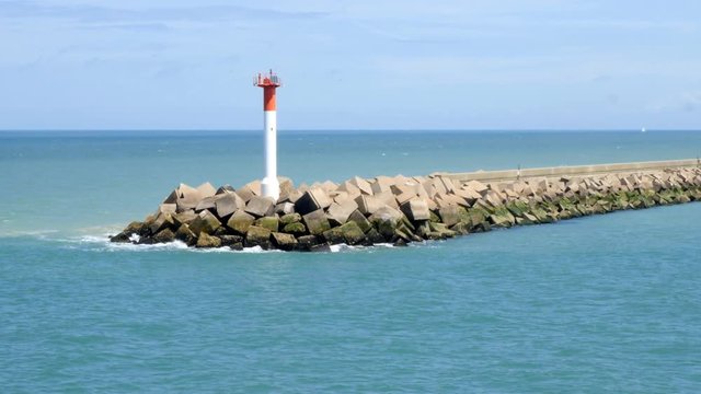 Breakwater or jetty with beacon sea mark powered by solar panel at the entrance to the port of Dunkirk, France