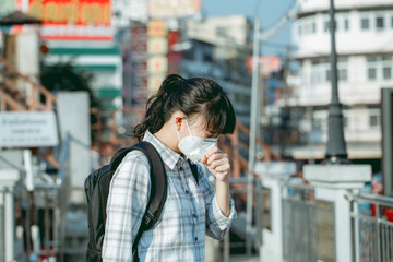 A student asian girl wearing PM 2.5 dust mask are in a city full of dust and smoke.