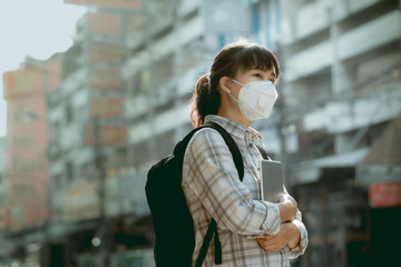 A student asian girl wearing PM 2.5 dust mask are in a city full of dust and smoke.