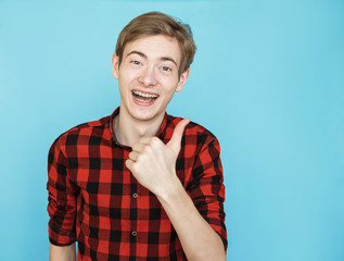 young male teenager in red shirt on blue background shows class