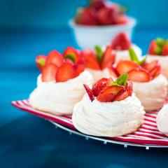 Strawberry pavlova cake nests, with mint on blue table