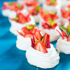 Strawberry pavlova cake nests, with mint on blue table