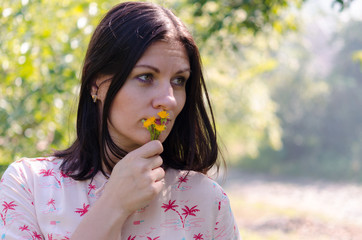 Portrait girl outdoors. Beautiful relaxing woman enjoying the fresh air on a sunny summer day against a background of nature with wildflowers.