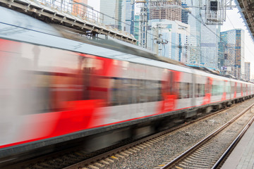 Fototapeta premium High-speed train running in the city against the backdrop of skyscrapers.