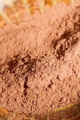 Fototapeta na wymiar Dry cocoa powder poured into a brown ceramic plate