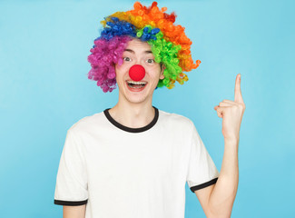 young funny male teenager in white t-shirt on blue background in clown wig has iedea