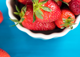 fresh bright strawberries in a bowl top view on a blue background