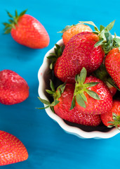 fresh bright strawberries in a bowl top view on a blue background
