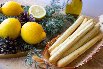 Breadsticks (grissini) on wicker plate, lemons, and olive oil