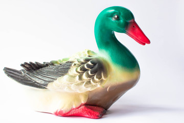 Ceramic statuette of a duck on a white background with brightly colored feathers. Duckling with...