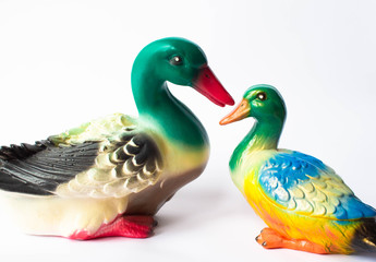 Ceramic statuette of a duck on a white background with brightly colored feathers. Duckling with mother duck