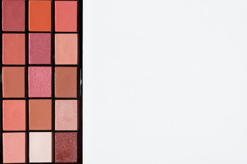 Top view of make up cosmetic - eyeshadow palette in pink and red colors on left side. Copy space on white background.