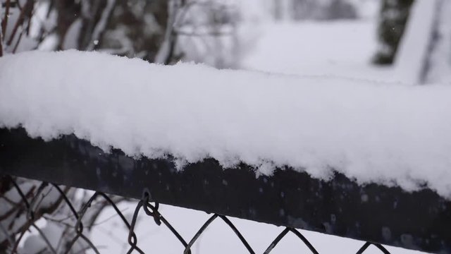 fresh snow falling over industrial fence - slow motion - slide down to upp
