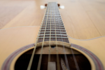 Guitar detail with part of body and neck, laying on a wooden floor
