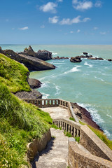 Biarritz, France. Atlantic ocean coastline. Old stone stairs on slope of green hill. Sunny summer day
