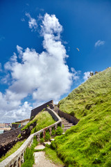 Old stone stairs on slope of green hill. Sunny summer day with blue sky and white clouds. Located...