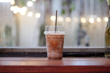 hand holding a glass of iced dark cocoa latte fresh milk mixed with cocoa sauce making marble texture