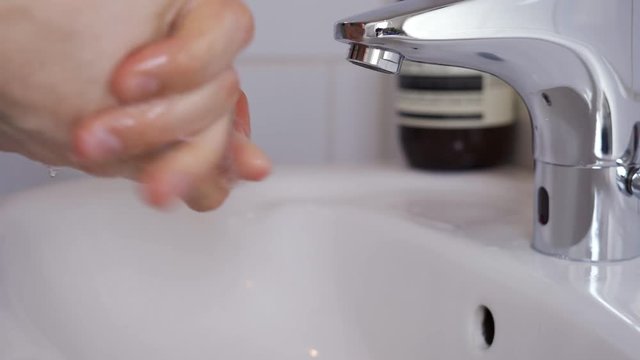 Man washing his hands by a touchless faucet