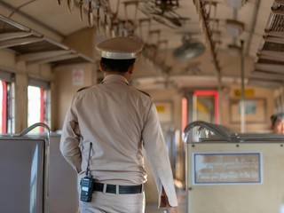 The train officers are checking passenger tickets on the train