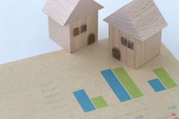 紙の上に書かれた棒グラフとミニチュアの家の模型