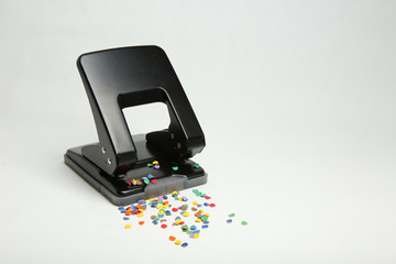 black office hole punch with confetti isolated on white background.  Hole puncher sprinkled whith...