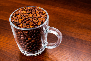 Roasted coffee beans in a glass cup isolated on a rustic dark wood table background