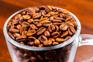 Roasted coffee beans in a glass cup isolated on a rustic dark wood table background