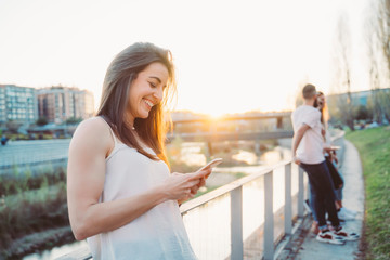 Happy woman texting on smart phone in street