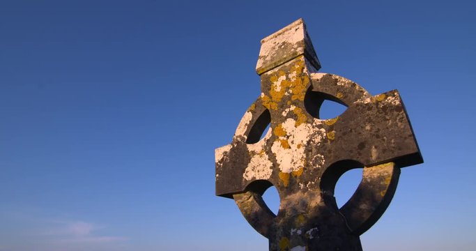 Ancient Irish celtic cross graveyard cemetery church building ruin golden sunshine blue sky