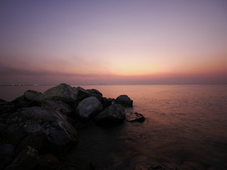 Fototapeta na wymiar Ocean water rushing by a rock on twilight time.