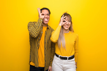 Young couple over vibrant yellow background makes funny and crazy face emotion