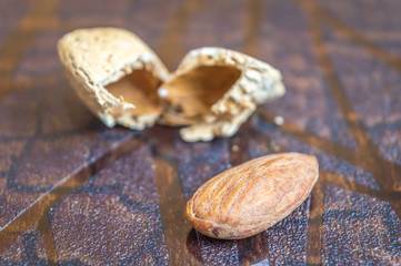Almond fruit broken from the brown almond shell on a brown wooden background