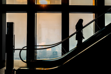 Silhouette of photographer woman standing on Escalator at the Mall.