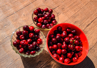 Berries of a sweet cherry on a wooden background in a plastic cup. Ripe red sweet cherry
