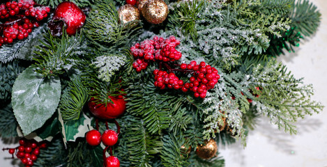 Christmas composition of pine branches, golden Christmas decorations, red berries and artificial snow.