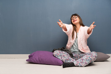 Woman in pajamas on the floor presenting and inviting to come with hand