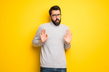 Man with beard and turtleneck making stop gesture with both hands