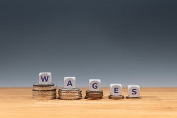 Symbol for declining wages. Dice placed on stacks of coins form the word 