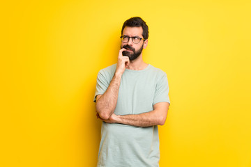 Man with beard and green shirt having doubts while looking up
