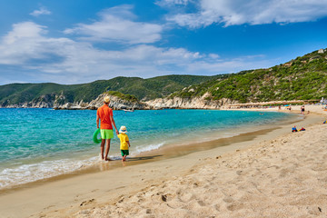 Toddler boy walking on beach with father
