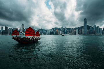 Naklejka premium Hong Kong City skyline with tourist sailboat. View from across Victoria Harbor Hong Kong.